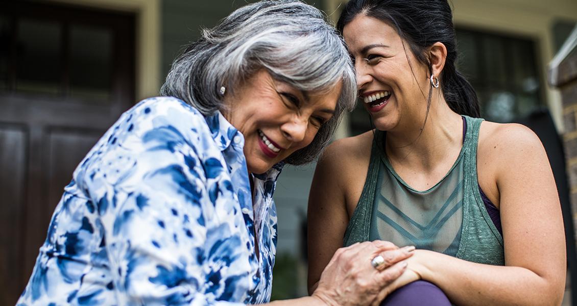 Woman smiling while holding older woman's hand